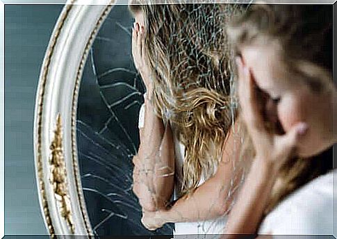 Distressed woman in front of broken mirror