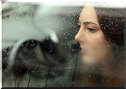 girl looking through a wet window