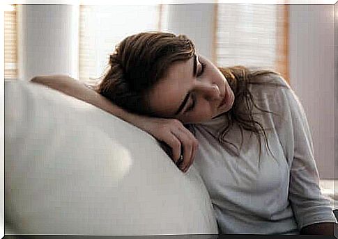 Depressed girl with her head resting on the sofa.