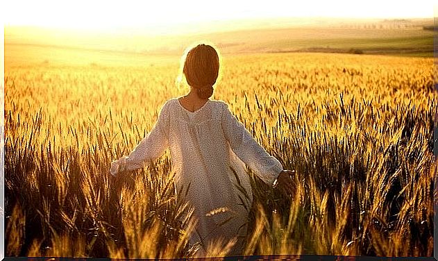 Woman dressed in white walking in wheat field