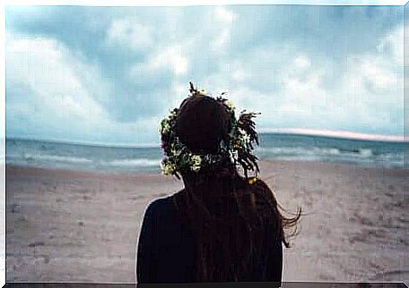 Girl from behind looks at the sea on the beach.