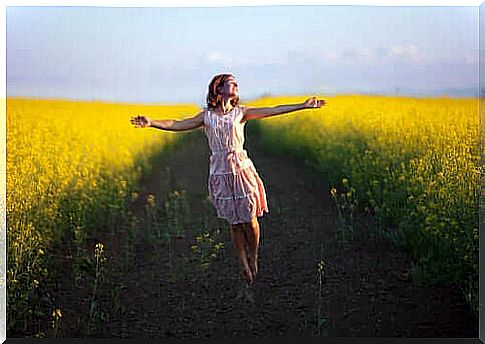 Happy woman in the middle of a path among the flowers.