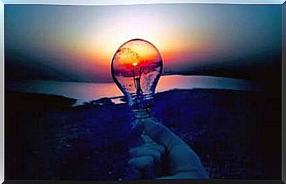 Hand with light bulb and sunset.