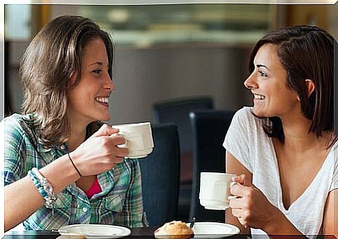 Women looking at each other and drinking coffee